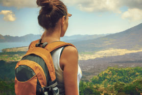 Junge Frau mit Rucksack schaut auf Landschaft