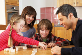 Eltern mit zwei Kindern spielen Domino