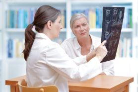 Arzt und Patient beim besprechen von Röntgenbilder des Kopfes