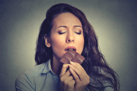 Frau isst mit verzückten Gesichtsausruck Schokolade